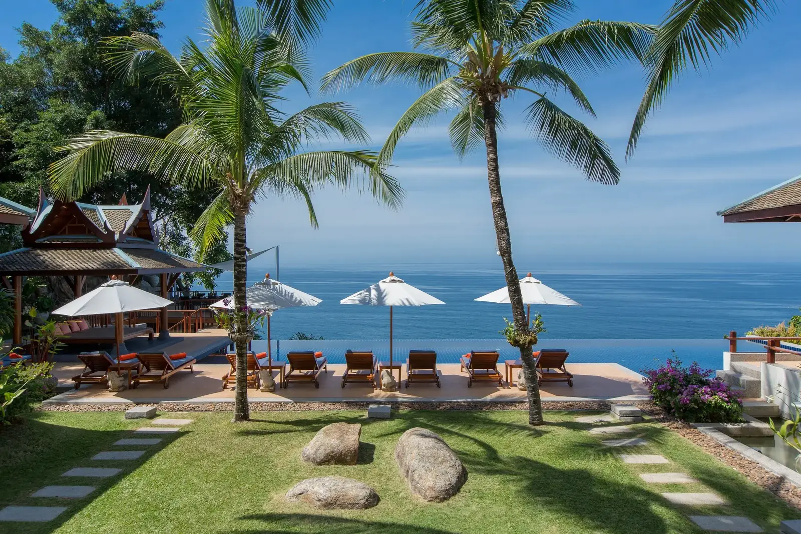 The central lawn at Villa Talaefun opening onto the infinity pool, with sun loungers, white umbrellas and the Andaman Sea beyond